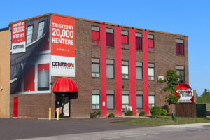 A large brick building featuring a prominent red awning at its entrance, showcasing a welcoming atmosphere at centron storage office in Toronto.